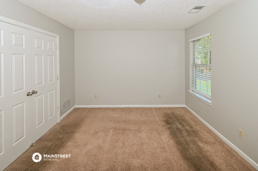 a bedroom with a carpeted floor and a white door