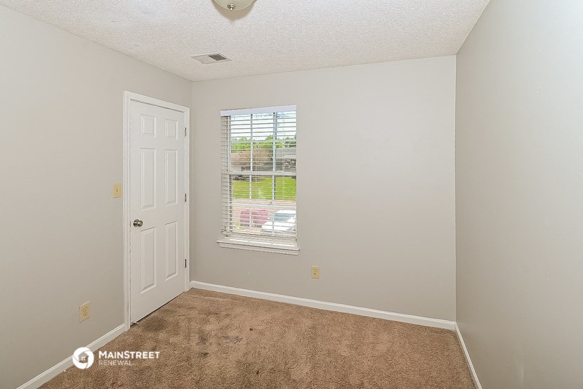 an empty bedroom with a window and a door
