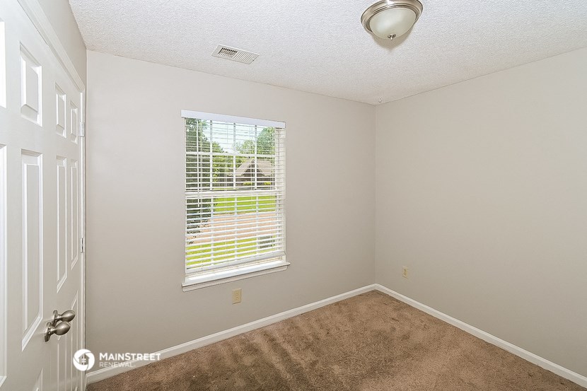 an empty bedroom with a window and a carpet