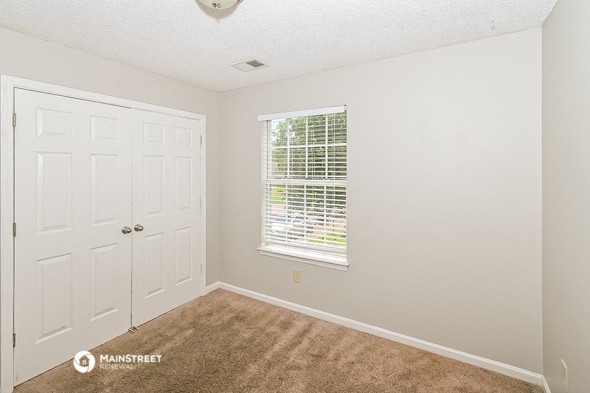 an empty bedroom with a door and a window