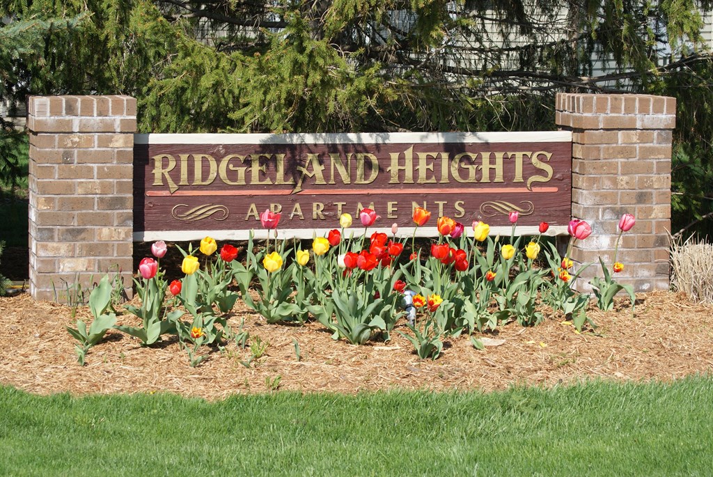 a sign apartments in front of a flower garden