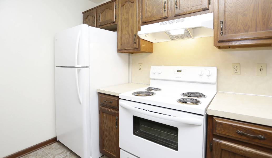 a kitchen with white appliances and wooden cabinets and a refrigerator