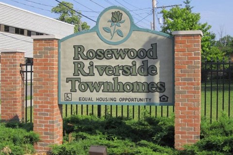 a sign for rosewood riverside townhomes in front of a fence