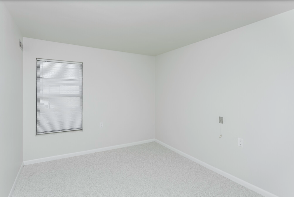 an empty room with white walls and a window
