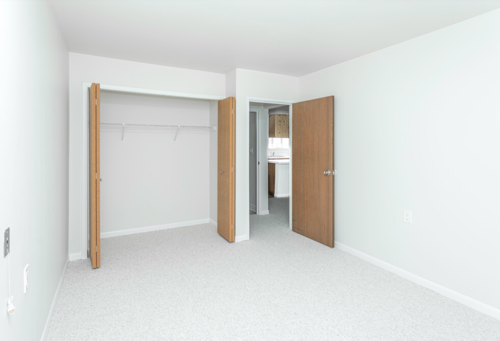 an empty bedroom with two doors and a closet