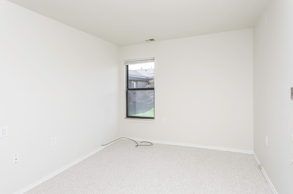 an empty room with a window and white walls