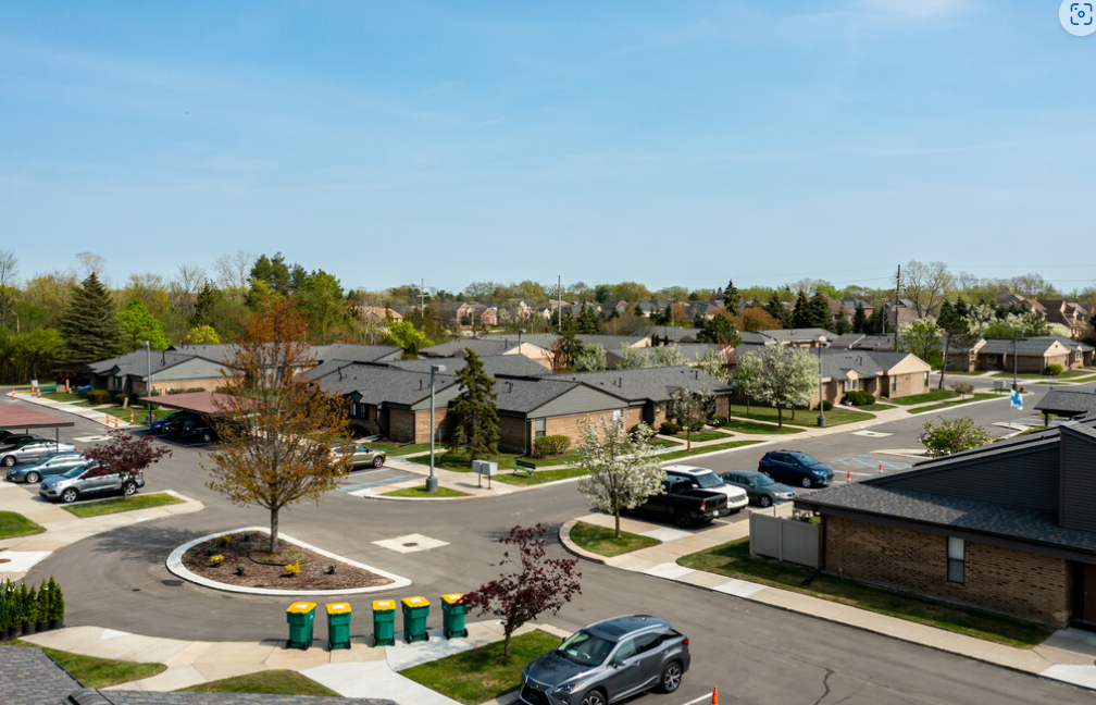 an aerial view of a suburban neighbourhood with a parking lot and cars
