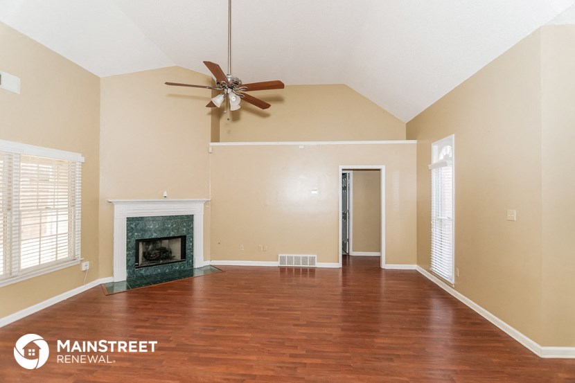 an empty living room with a fireplace and a ceiling fan