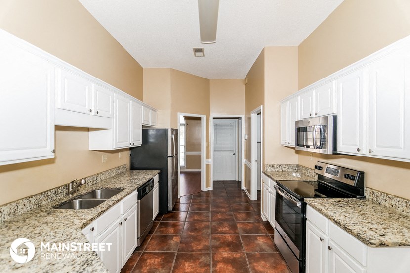 a kitchen with white cabinets and black appliances and granite counter tops