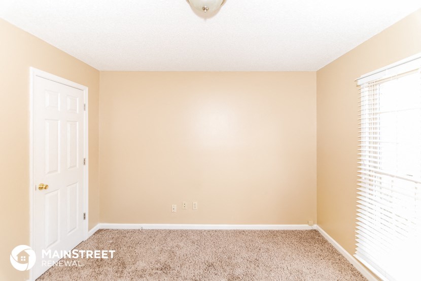 a bedroom with a white door and a carpeted floor
