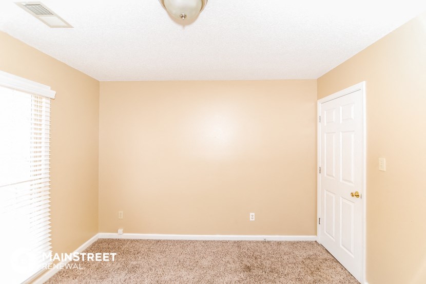 a empty living room with a white door and carpet