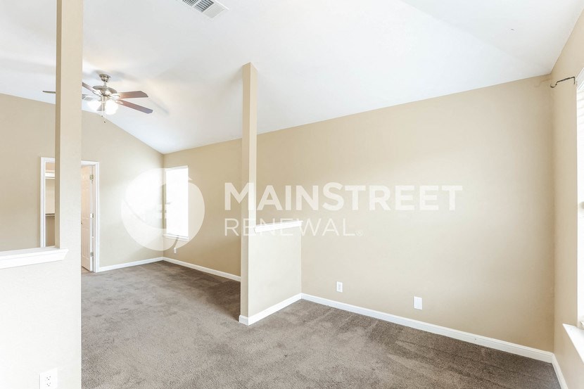 a living room with carpet and a ceiling fan