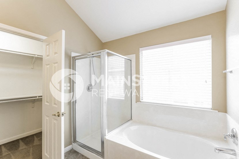 a bathroom with a tub and a shower and a window