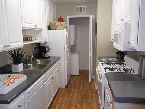 A kitchen with white cabinets and a white fridge.
