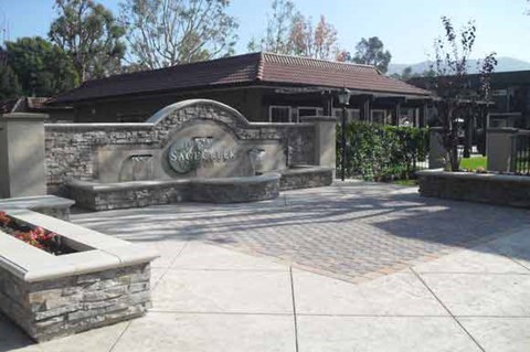 A stone monument with a plaque on it is in front of a building.
