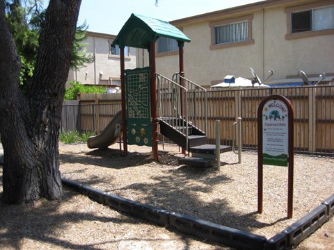 A playground with a green roofed structure and a slide.