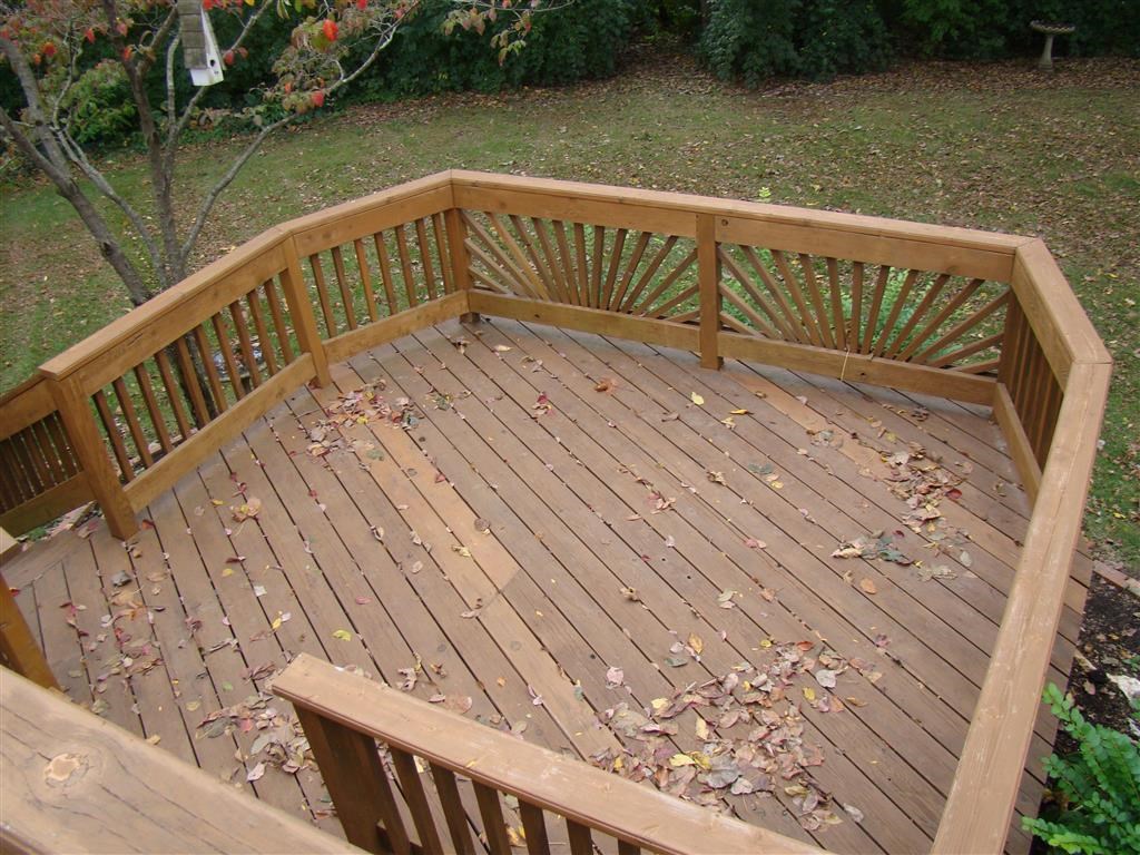 a wooden deck with a wooden railing in a backyard