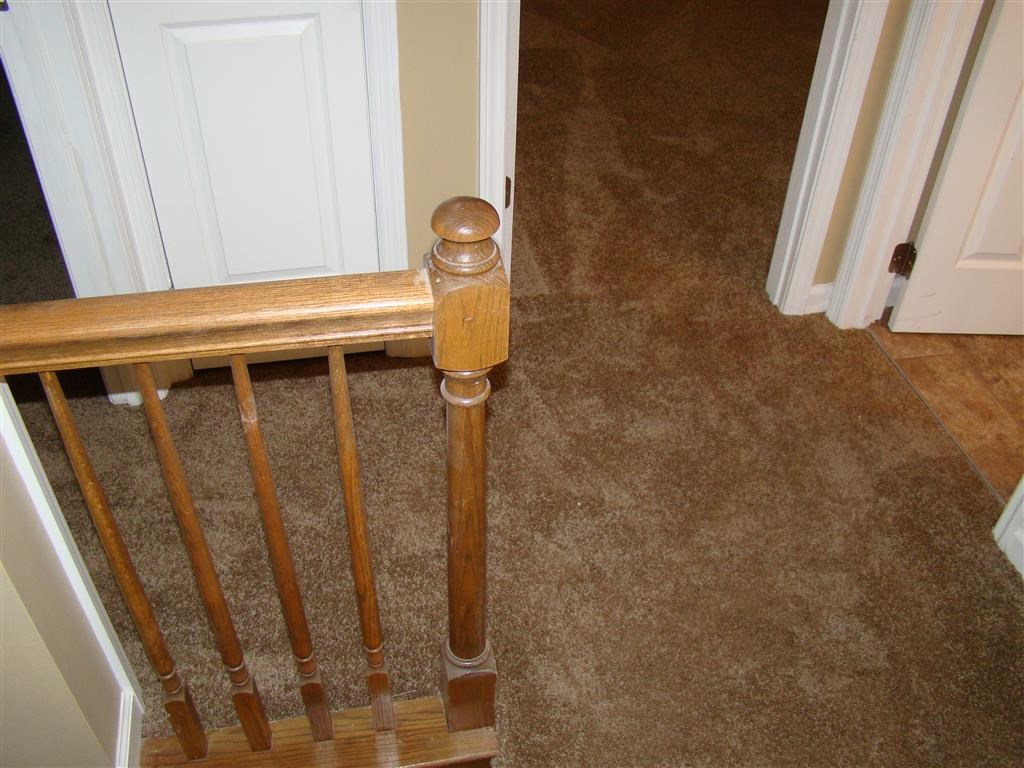 a staircase with a wooden railing on a carpeted floor