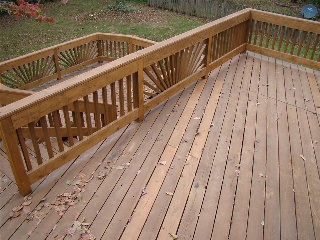 a deck with a wooden railing and a yard in the background