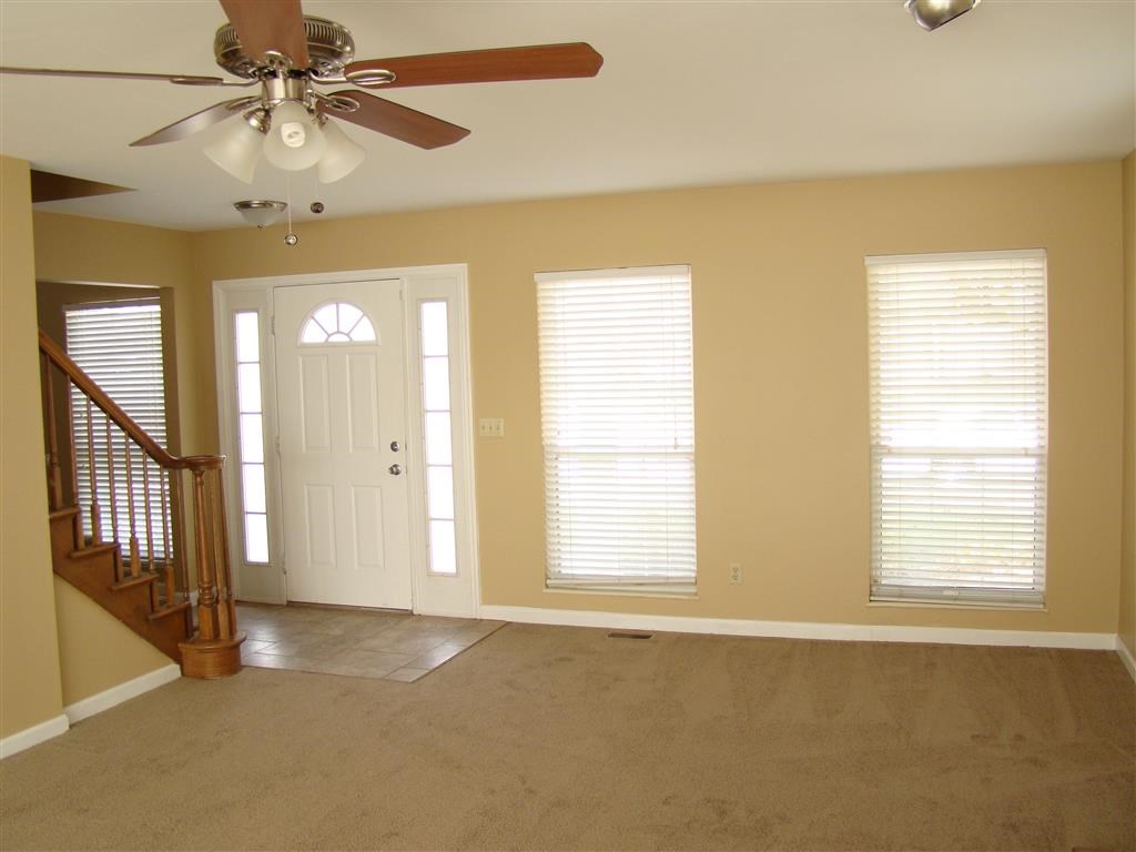 an empty living room with a ceiling fan and a door