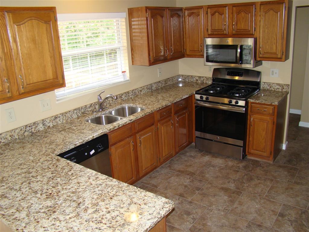 a kitchen with granite counter tops and wooden cabinets