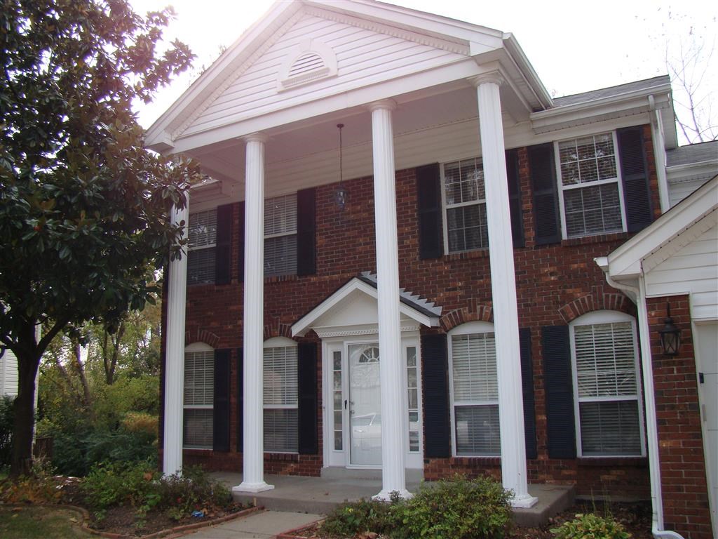 a front porch with columns in front of a brick house
