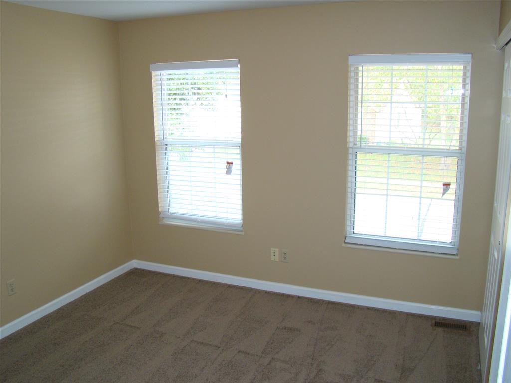 a empty room with two windows and a wooden floor