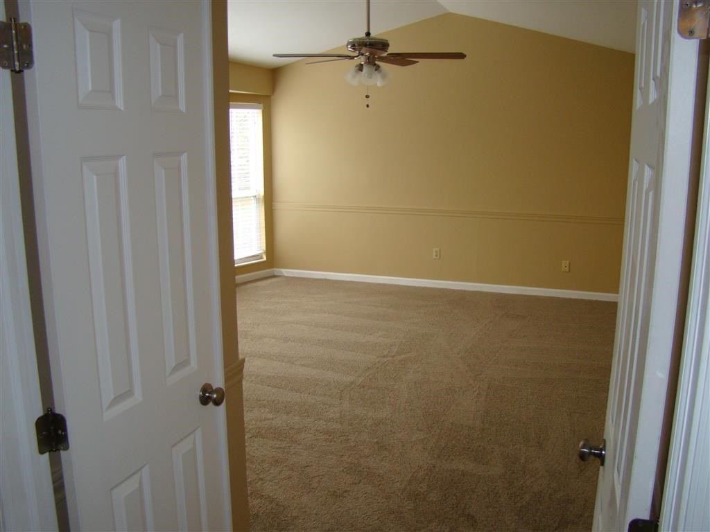 an empty room with a ceiling fan and a white door