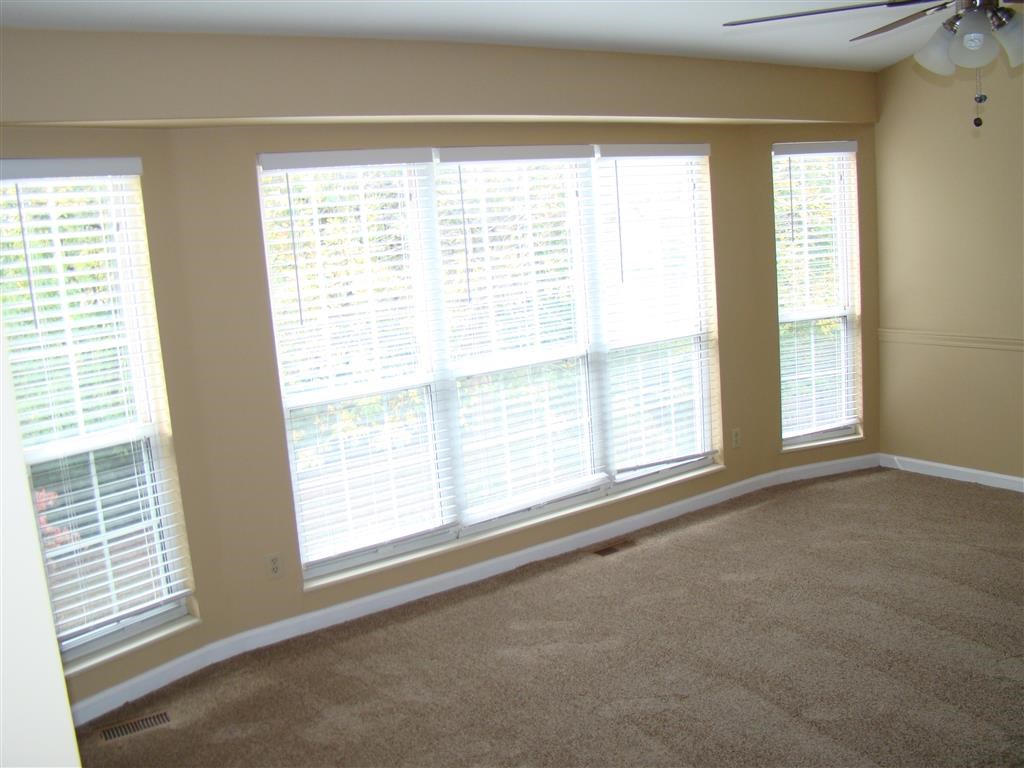 a living room with a large window and a ceiling fan