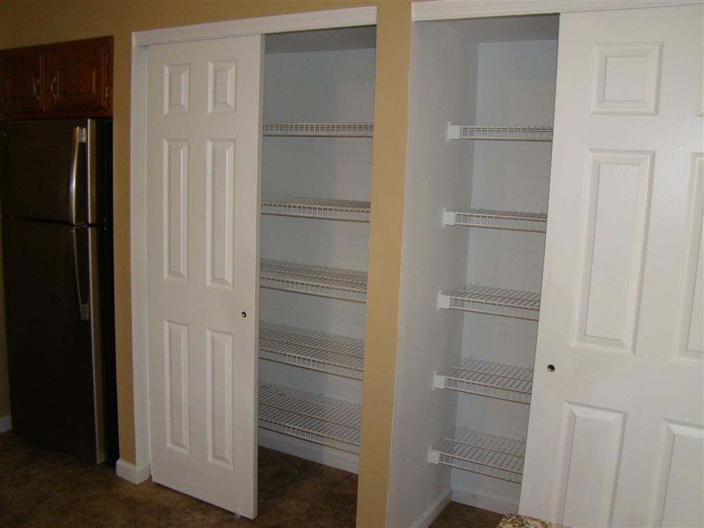 an empty closet with two doors and a refrigerator