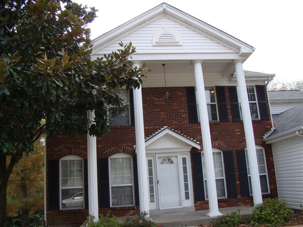 a brick house with white pillars and a white door