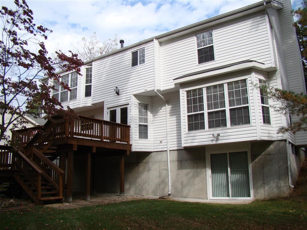 a view of the back of a white house with a wooden deck