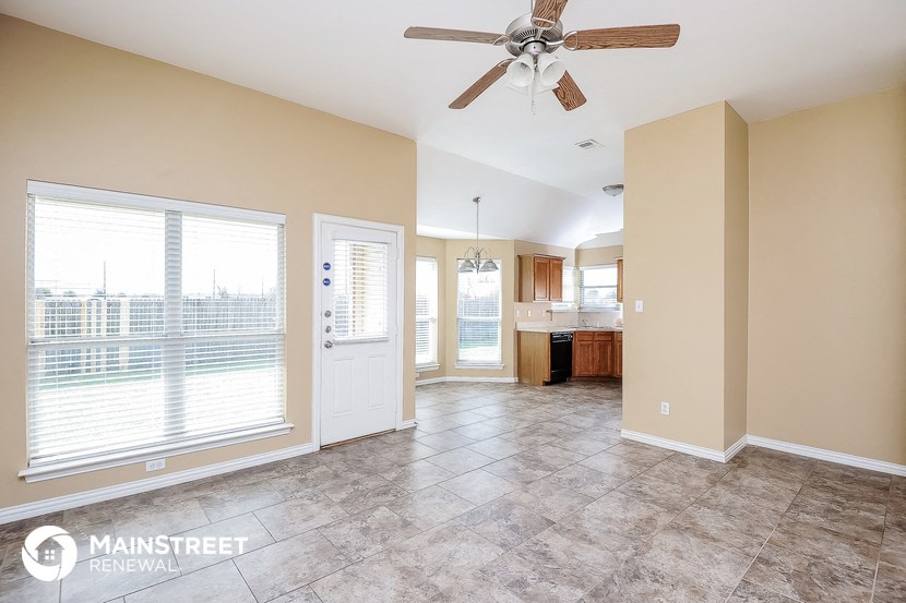 an empty living room with a ceiling fan and a kitchen