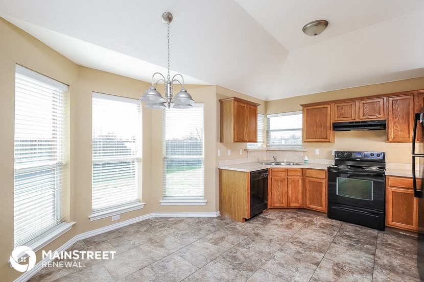a kitchen with wood cabinets and black appliances and a large window