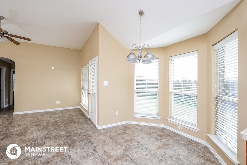 an empty living room with three windows and a ceiling fan