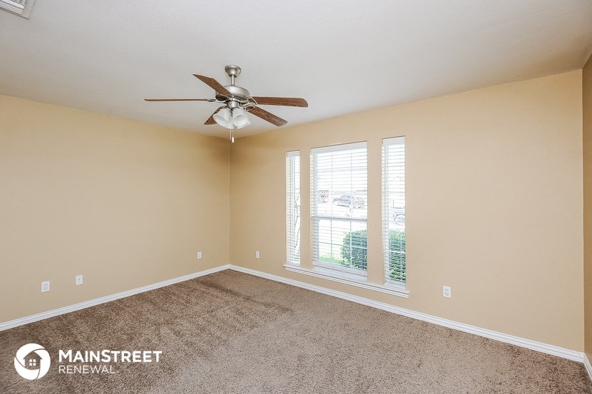 the master bedroom has carpet and a ceiling fan