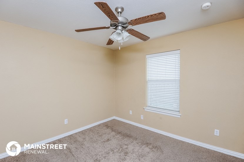 the master bedroom has a ceiling fan and a carpeted floor
