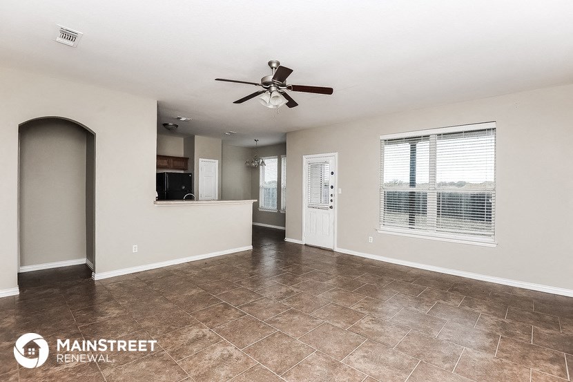 an empty living room with a ceiling fan and a window