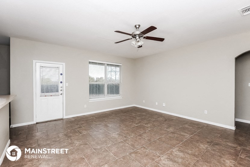 an empty living room with a ceiling fan and tile flooring