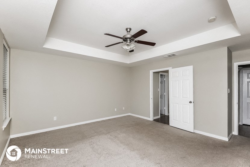 the master bedroom has a ceiling fan and carpet