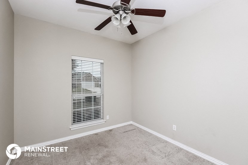 the living room of a home with a ceiling fan and a window