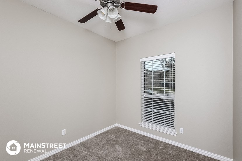 the bedroom has a ceiling fan and a window