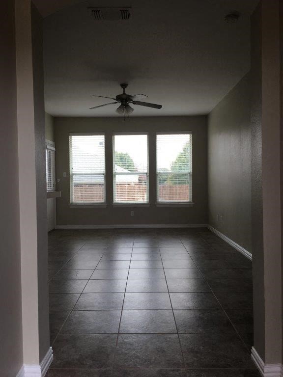 a empty living room with a ceiling fan and windows