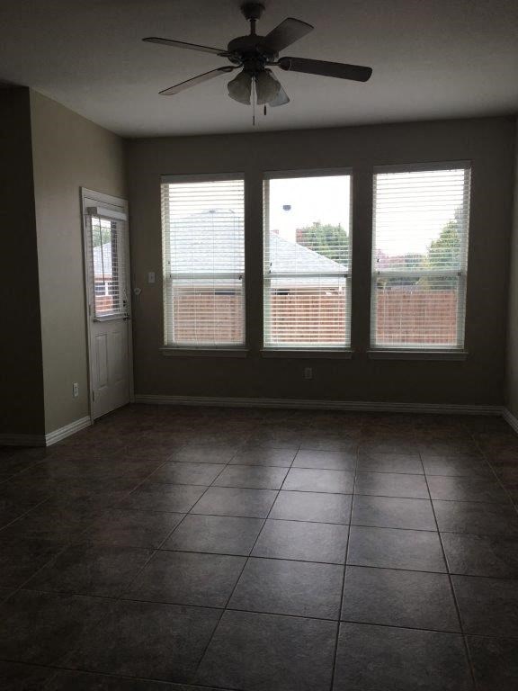 an empty living room with a ceiling fan and three windows