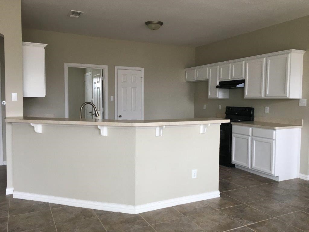 an empty kitchen with white cabinets and a counter top
