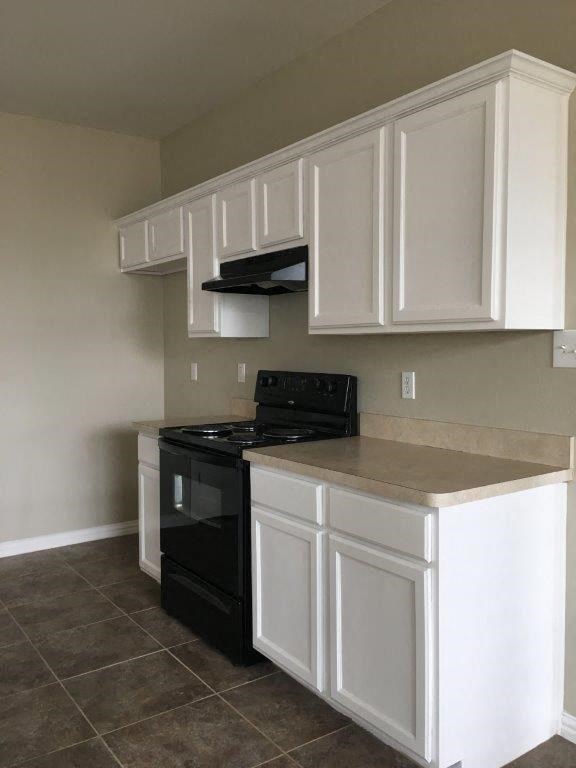 a kitchen with a black stove and white cabinets