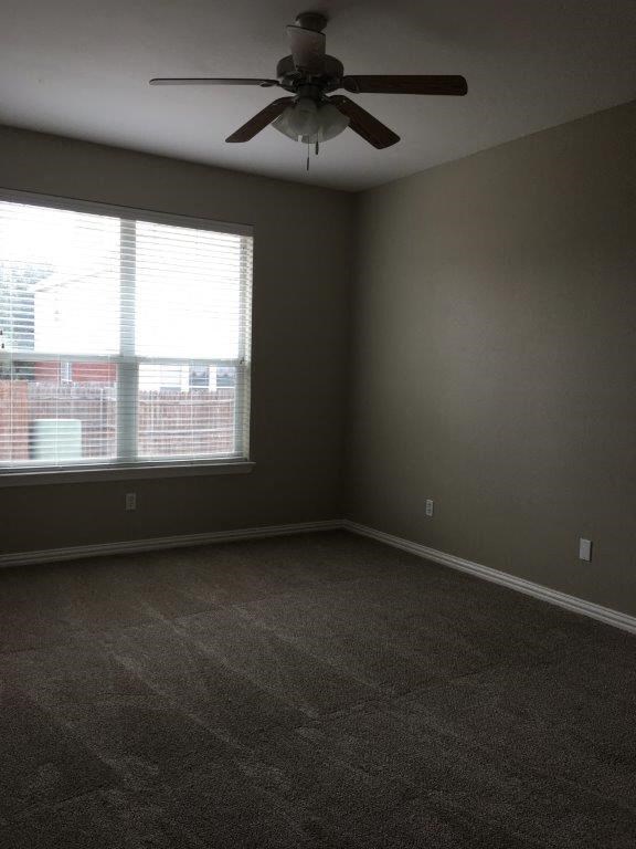 an empty living room with a ceiling fan and a window
