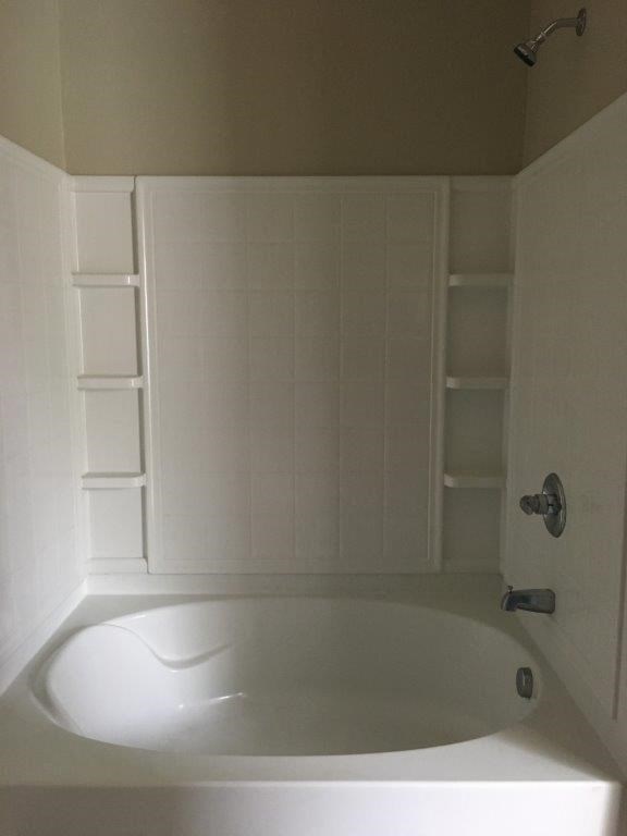 a white bathroom with a bath tub and white shelves