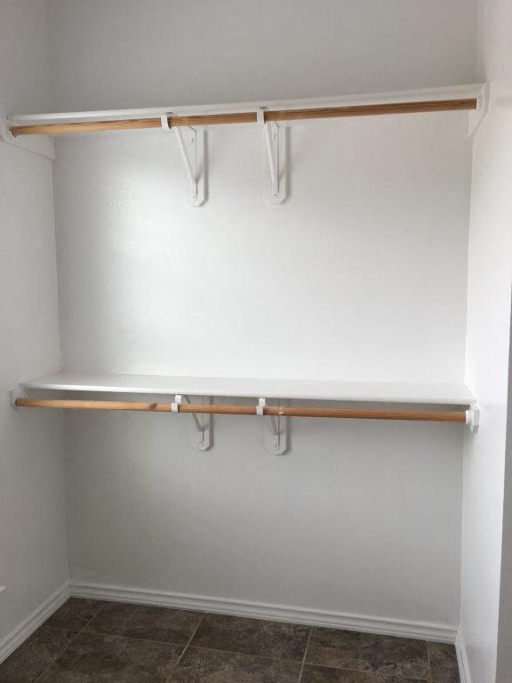 an empty closet with a shelf and hooks on the wall