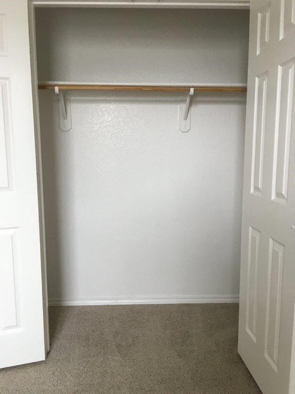an empty closet with a white wall and a white door